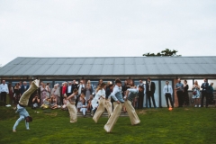 A group of guests are having a sack race on the lawn in front of the Red Brick Barn