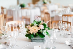 Table set up with round tables, white linen, cheltenham chairs and floral centre-pieces