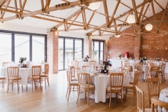 A picture showing the Red Brick barn set up for the wedding meal with round tables
